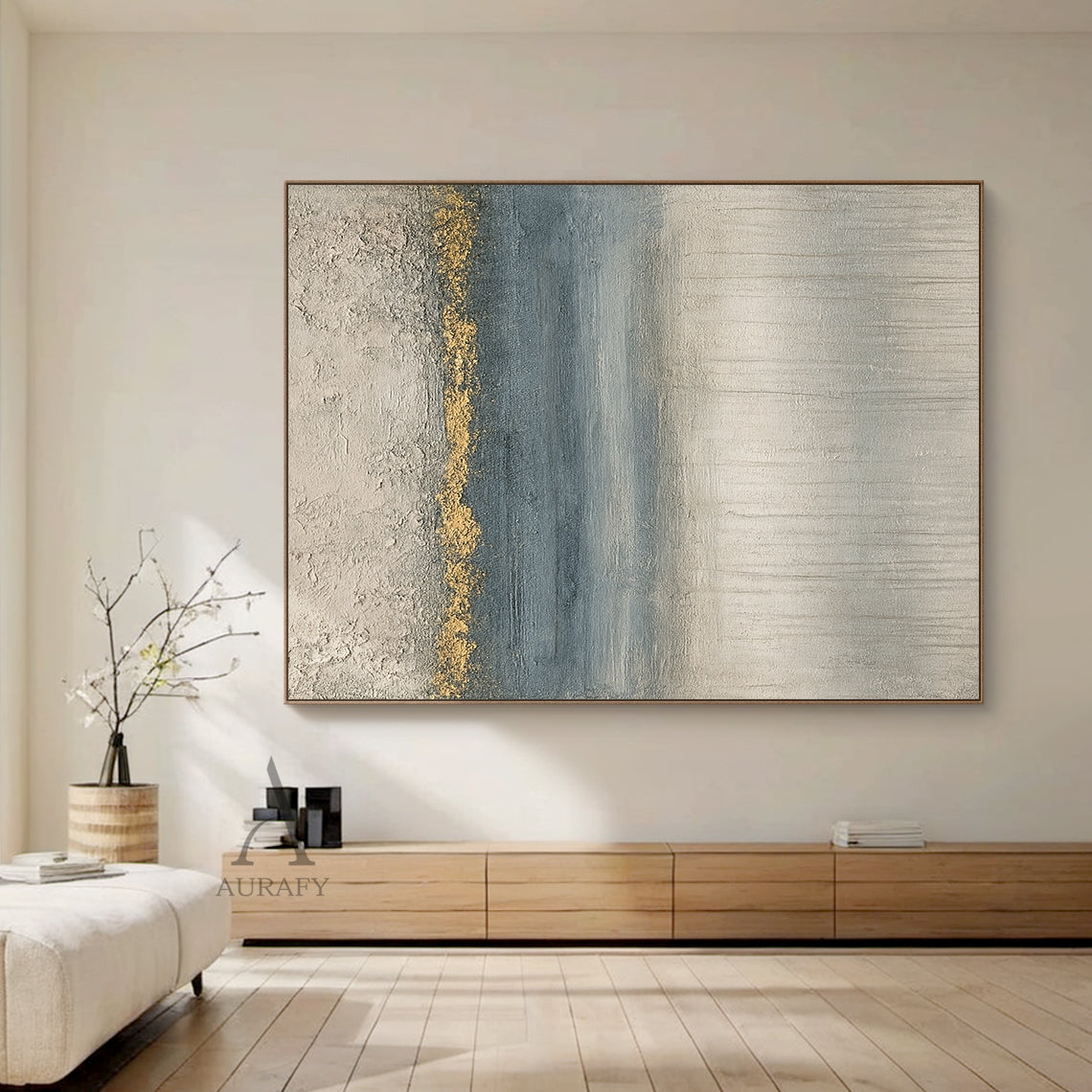 General abstract gray blue plaster textured wall art (AURA405) shown in styled modern home scene, with its iconic horizontal layered composition: top rough thick impasto light gray plaster texture, middle irregular textured gold accent band as visual focal point, followed by gradient blue section with horizontal brushstrokes, bottom light gray layer with vertical dripping texture. This modern organic wabi-sabi style artwork blends perfectly with surrounding neutral home furnishings, ideal for Japandi, minim