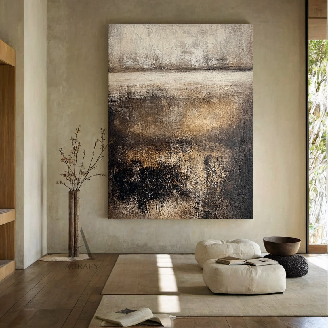 Horizontal earthy brown abstract textured painting SKU AURA617 in real japandi home styling scene: the wabi-sabi minimalist organic artwork is mounted on light beige textured wall above a low solid wood sideboard, matched with woven rattan ornament and dried reed arrangement placed on the cabinet top, the painting's layered structure is clearly presented under soft diffused natural light -- upper hazy section blending light off-white and pale beige, lower part with overlapping rich dark brown, charcoal blac