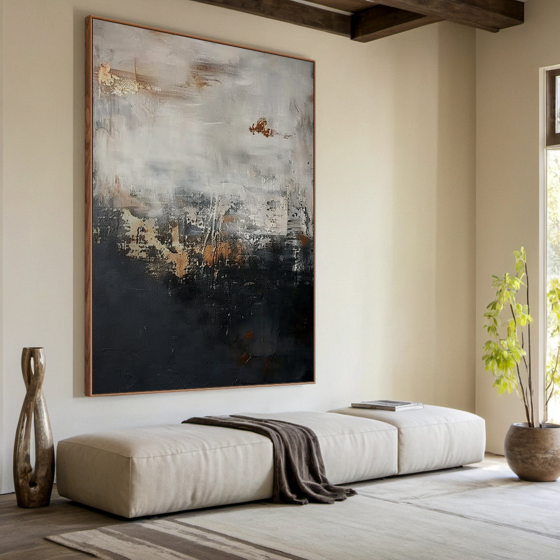 Wabi Sabi abstract sculpted canvas art with impasto knife strokes and tactile surface—deep black lower section, light gray upper layer, golden copper accents. Displayed in a cozy natural minimalist nook: warm oak desk, rattan armchair, potted fiddle-leaf fig, neutral linen curtains, soft natural light filtering through. Embraces Wabi Sabi’s imperfect beauty and subtle warm softness (Pink vibe) for calm, minimalist home decor. AURA196.