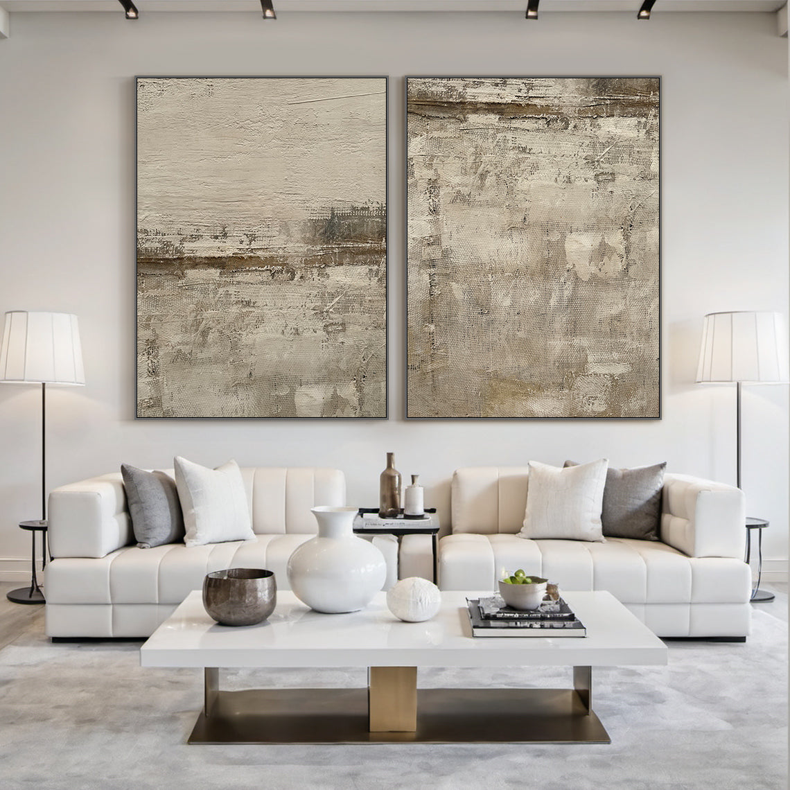 AURA227 Wabi Sabi Brown Abstract Wall Art Two-Piece Set—textured canvas with warm earthy tones (soft beige, rich brown, subtle gray) embodying organic imperfection. Displayed in a modern minimalist living room with neutral walls, white leather sofas, gray rug, and floor lamps. Ideal for contemporary interior decor, adding depth and sophistication to calm spaces. This two-piece abstract art set elevates living room ambiance with layered tactile details, perfect for pairing with minimalist furniture and neutr