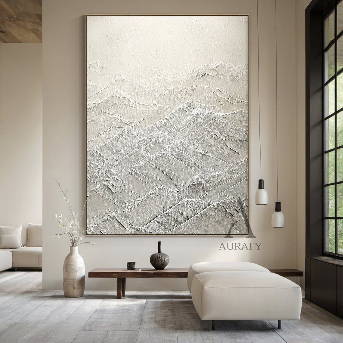 High-relief white abstract canvas art (AURA500) with thick tactile knife strokes and layered texture forming gentle peaks and valleys (evoking rolling mountains or serene waves). Monochromatic palette spanning soft ivory to crisp snow tones, merging modern minimalist style with subtle Wabi-sabi influences. Ideal focal point for Japandi spaces—perfect above a sleek wooden dining table in a sunlit eat-in kitchen, next to a woven rattan armchair in a quiet reading nook, or against a soft light gray tile wall i