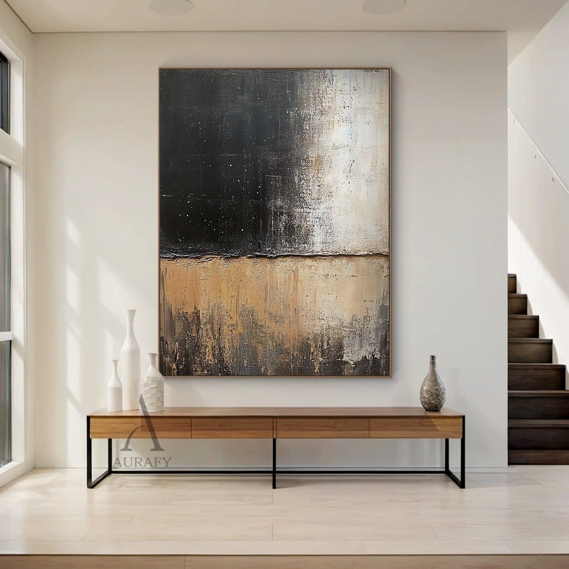 General abstract impasto canvas wall artwork AURA405, displayed as hanging decor in a warm minimalist Japandi bedroom scene above a low-profile natural rattan headboard against a soft matte warm white wall: it retains the iconic horizontally split textured composition, upper zone with thick textured deep black paint scattered with tiny white star-like specks gradually fading to muted light beige, lower zone with layered earthy beige, warm tan and dark brown tones with vertical dragged brushstrokes presentin