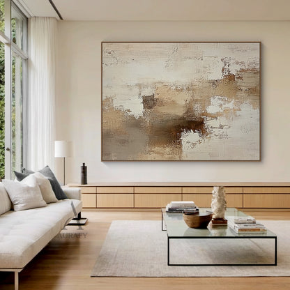 AURA634 abstract beige textured canvas wall art home display shot, the artwork is installed on a light plain wall to present its real decorative effect in actual space. It features a neutral palette of soft beige, layered varying tan brown shades and warm off-white with gentle color transitions. The surface has clear handcrafted texture with visible thick impasto, scratch, and paint stacking brush strokes, blending uneven paint texture with canvas base texture. It has no specific figurative elements, compos
