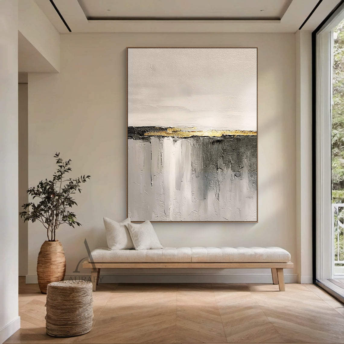 Hand-painted beige abstract impasto canvas wall art AURA718, displayed hanging on a matte warm taupe bedroom accent wall above a white washed oak low-profile bed frame in a soft cozy neutral home styling scene, the artwork features soft warm off-white and light beige with subtle thick paint grain texture on the upper section, central horizontal matte charcoal stripe accented with raised grainy metallic gold thick paint band as focal point, lower area is gradient gray from light beige gray to dark charcoal w