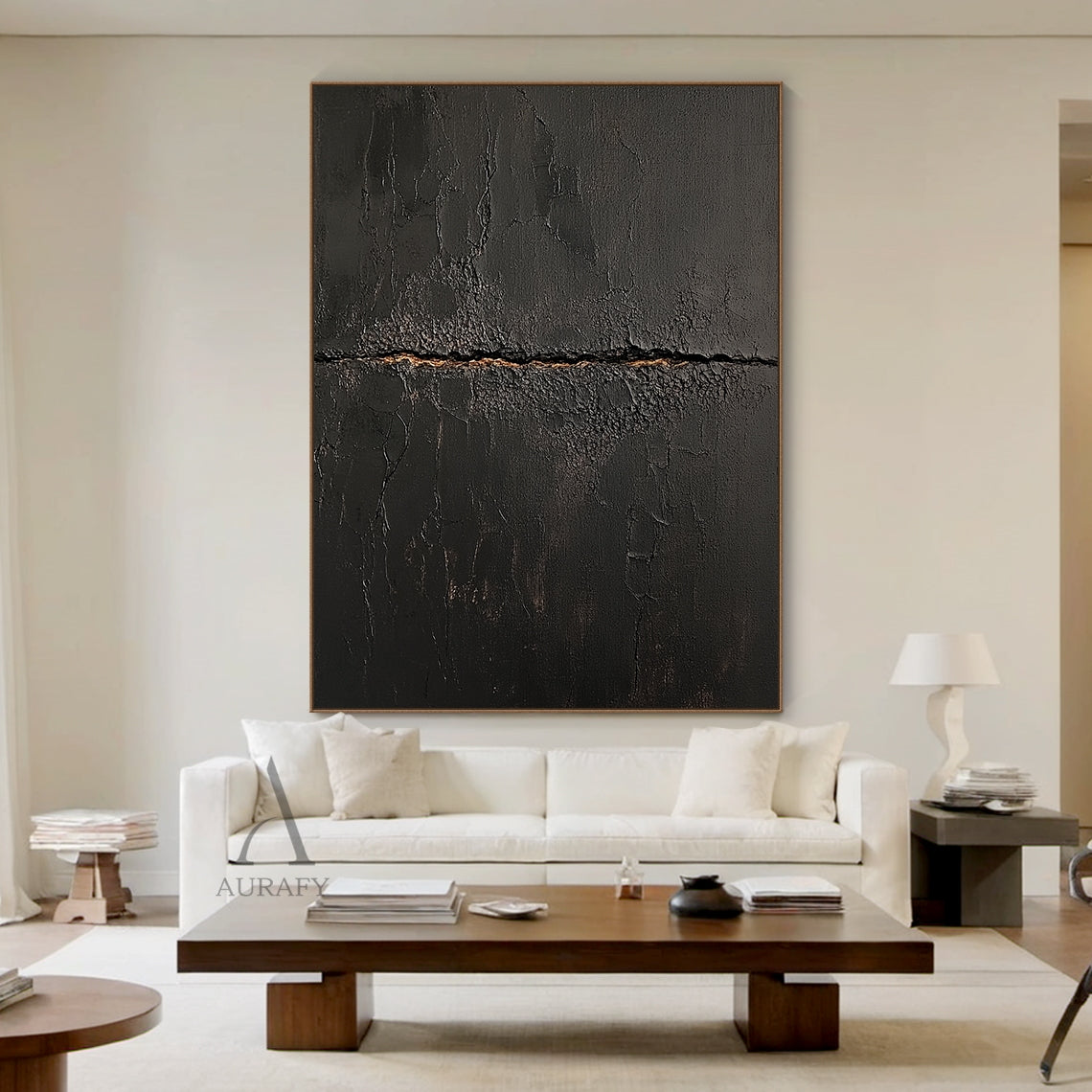 Black abstract textured impasto canvas wall art AURA723 hung above low-profile dark linen sofa in moody modern living room, deep matte black surface with heavy crackle texture resembling aged cracked lacquer or charred earth, a rough horizontal split runs across the center of the piece with subtle warm earthy gold underlayer exposed, fine organic fissures spread out from the split, raw wabi-sabi tactile artwork perfect for elevating dark minimalist, japandi and contemporary interior decor