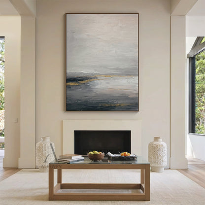 General Abstract gray beige canvas wall art (AURA626) displayed in Nordic light luxury dining room interior scene, features the signature layered muted gray shades (light, medium, dark) base with soft beige transition zones, accented with subtle shimmering golden streaks and patches. The tactile textured brush stroke layers present well against the creamy white backdrop: loose hazy upper light gray and beige areas evoke misty mountain fog imagery, thick deep gray lower sections mimic calm lake surface, gold