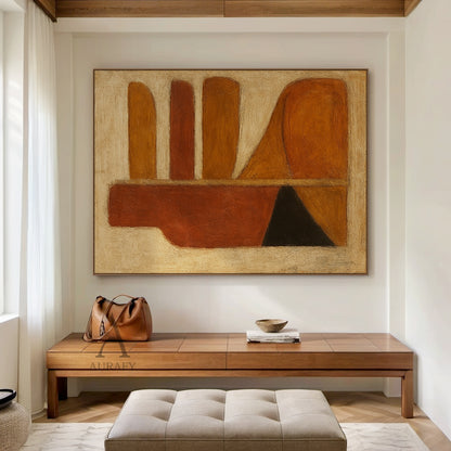 Handcrafted abstract brown wall art with tactile brushstroke texture and organic geometric composition, styled in a bright open-concept home dining space. The piece retains its signature design: left side with a vertical deep rust red-brown bottle-shaped silhouette, matched with black and orange-brown triangular blocks at the base, right side with rounded horizontal strips in warm amber, rust and brown tones plus curved orange-brown blocks, all set against a muted off-white textured background. This warm mi