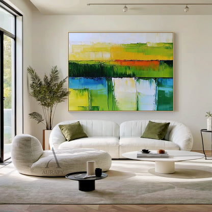 Horizontal green blue abstract impasto canvas wall art home scene display (AURA405), crafted with thick knife-painted texture for 3D tactile surface. Features layered horizontal color blocks in shades of green (lime, deep forest green), blue (soft sky blue, rich teal), accented with warm yellow, orange and creamy white blocks. The non-figurative abstract artwork evoking natural scenery of sunlit landscapes and calm waterways is presented in a real interior space to show its perfect matching effect for Japan