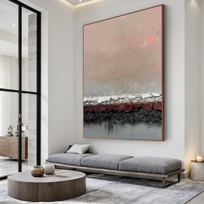 Vertical abstract art painting with layered textures: soft blush pink upper section, muted taupe gradient, textured white-silver crackle band, deep burgundy red layer, charcoal black crackle base, and cool gray bottom. Framed in warm metallic border, displayed on a light gray concrete accent wall in a minimalist modern study paired with a walnut writing desk and black leather ergonomic chair—ideal statement decor for contemporary living areas, home offices, or dining room focal points. This piece blends ear