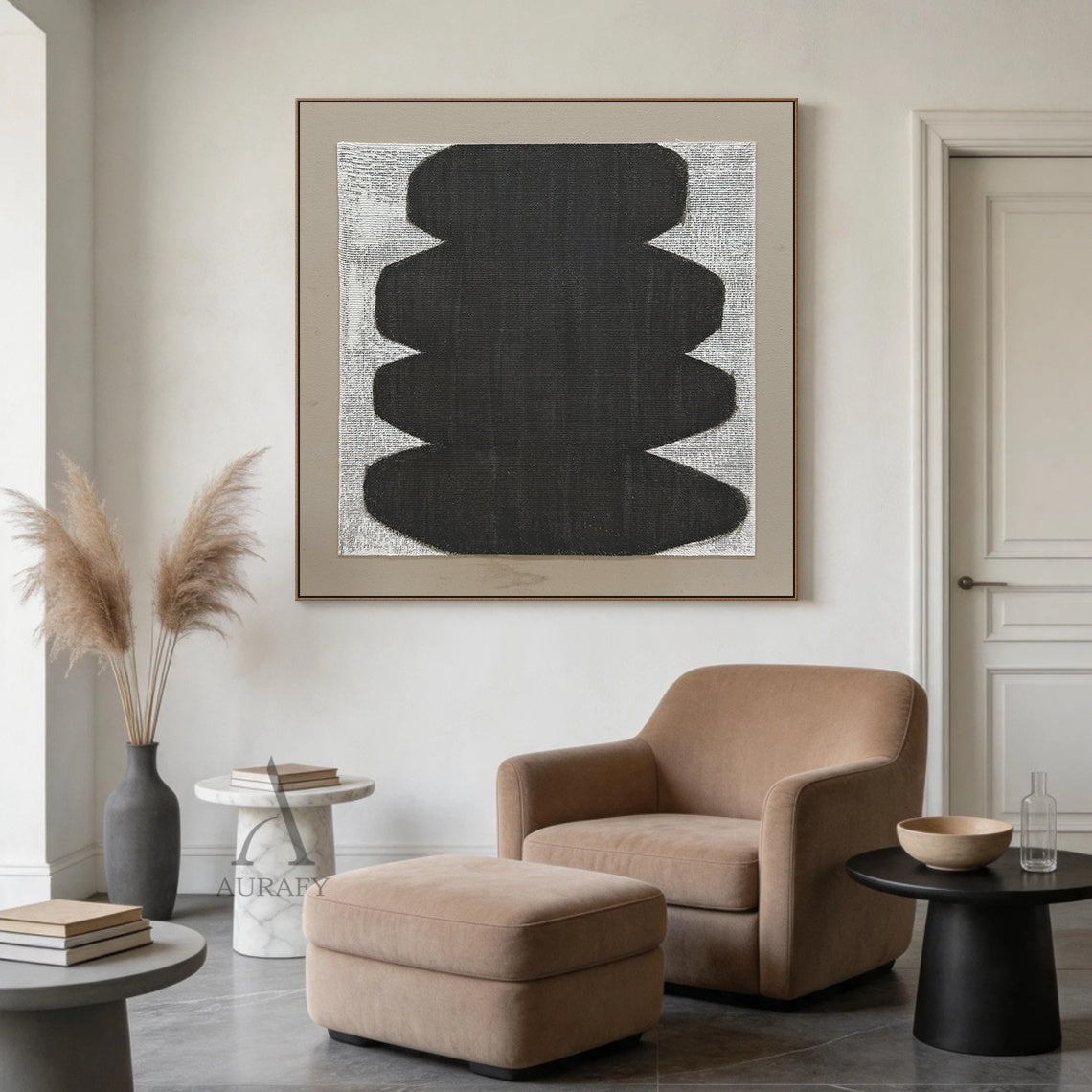 Minimalist abstract Japandi wabi-sabi wall artwork AURA727 staged in a calm curated modern living room, square raw woven canvas with clear grid texture is mounted on off-white plaster wall above a low light oak sideboard, features stacked soft curved matte black organic form with no sharp edges, uses monochrome black, white and neutral gray color palette, canvas weave texture is visible through both painted and unpainted areas, paired with a light taupe matte border, styled alongside neutral linen soft furn