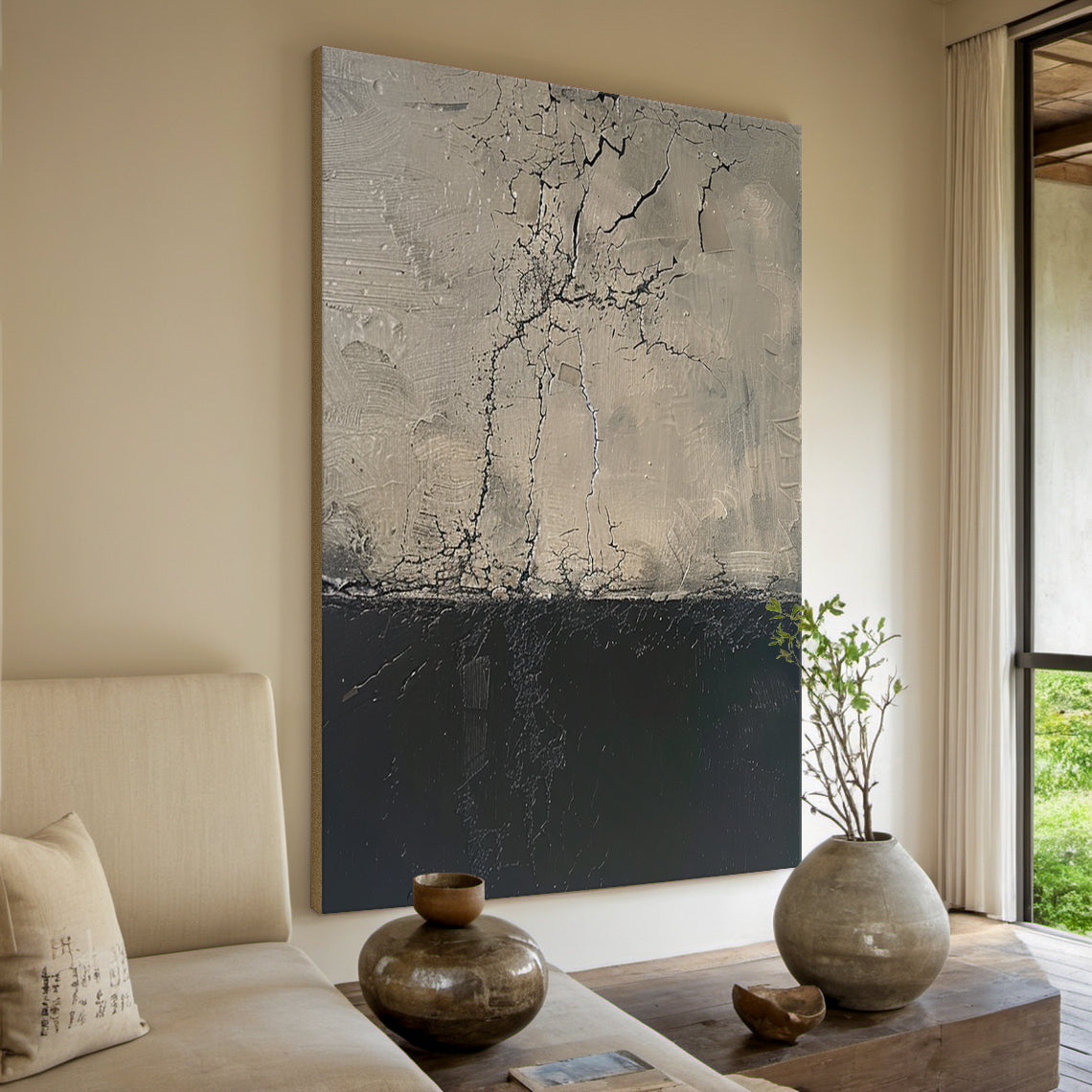 Vertical abstract painting with upper beige-gray section (crack-like linear patterns, impasto texture) and lower deep black section, framed in thin warm brown. Hung above a light gray velvet headboard in a serene modern bedroom: soft pale blue walls, light oak nightstands with ceramic vases holding dried flowers and minimalist silver table lamps, and a plush wool rug underfoot. This piece infuses the calm, cozy space with subtle artistic elegance.