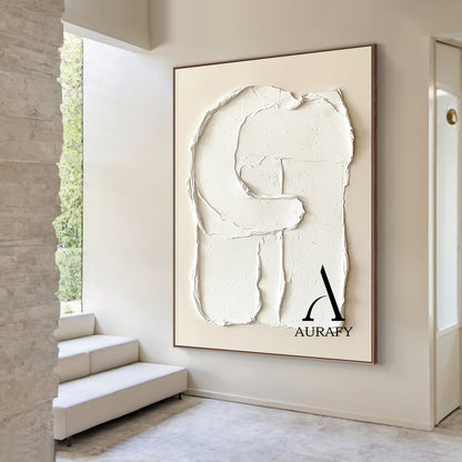 Aurafy AURA541 minimalist plaster textured wall art, warm soft beige canvas base with hand-applied thick impasto matte white 3D abstract capital letter G shape, with irregular handcrafted rough edges, natural porous surface details and texture folds, real shot hung on off-white matte living room accent wall, with light gray linen sofa and small teak side table in the background, neutral tone wabi sabi japandi wall decor for modern minimalist, Scandinavian and cozy neutral home.