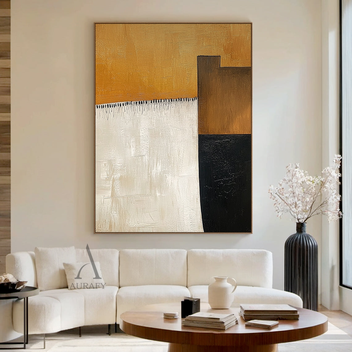 AURA641 Abstract Brown Beige Wall Art, modern organic abstract impasto painting with thick tactile brush strokes, presented hung in a real Japandi minimalist home scene above a light oak low cabinet. It features the signature large warm amber brown top block, vertical soft beige left block, dark brown and deep black geometric blocks on the right, with delicate black tassel-style short brush strokes as detailing between the brown and beige areas. All color blocks have clear visible hand-painted brush texture
