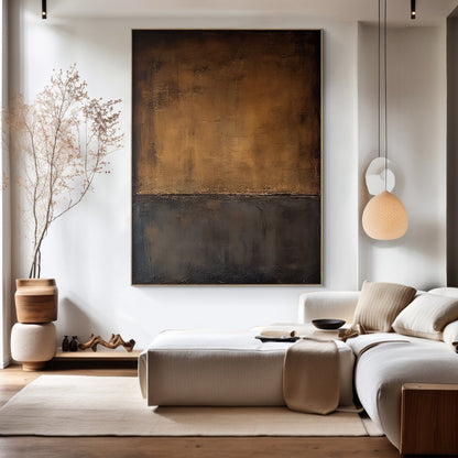 Vertical high-end abstract wall art with split composition: warm gold-brown upper half and deep black lower half, featuring tactile knife strokes and thick impasto texture. Hung as a statement piece in a Japandi modern minimalist living room with neutral tones—white sofa, wooden accents, jute rug, dried branches—embodying wabi-sabi's quiet elegance and imperfect beauty, perfect for grounding neutral spaces.