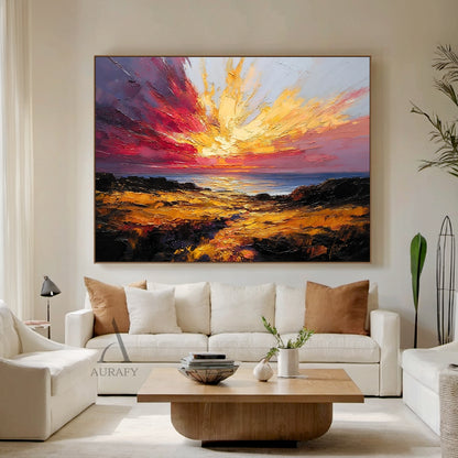 Textured palette knife impasto coastal sunset seascape painting, soft haloed golden sun sinks low above the sea level, intertwining with burnt orange, rose red and hazy mauve clouds stretching across the sky, rippling indigo sea below shimmers with scattered warm golden light spots, foreground is weathered taupe and gilded sun-kissed jagged reefs with foamy white waves lapping at the edge, thick raised sculptural impasto brushstrokes deliver lush tactile texture, striking warm-toned atmospheric coastal natu