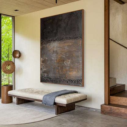 Wabi Sabi abstract art with high-relief tactile surface, bold knife strokes, and metallic foil accents in deep charcoal and warm taupe tones. Displayed in a minimalist living room (light gray linen sofa, solid wood coffee table, ceramic vase with dried branches, wool rug) — ideal for bringing a calm earthy vibe to organic Japandi living rooms, cozy neutral relaxation corners, or simple study spaces. This piece celebrates the beauty of imperfection, complementing natural materials like wood, linen, and wool 