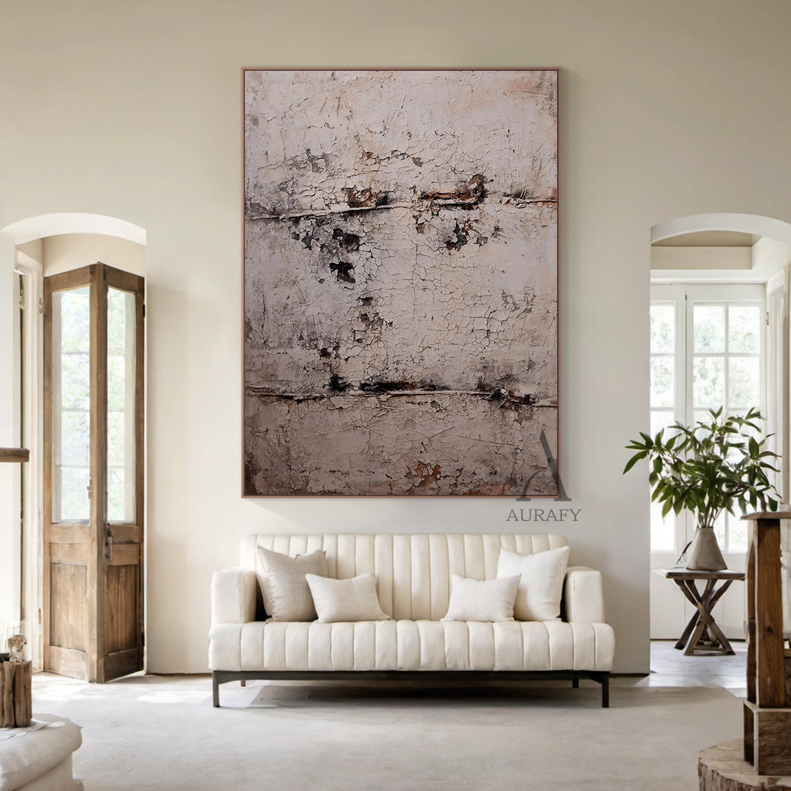 Large vertical abstract wall art with a textured, cracked surface in neutral beige, gray, and subtle brown/black tones, framed in a thin brown border. Displayed in a modern living room setting above a white tufted bench, next to a potted plant (terracotta pot) and beige table lamp—ideal for minimalist or contemporary home decor accents.