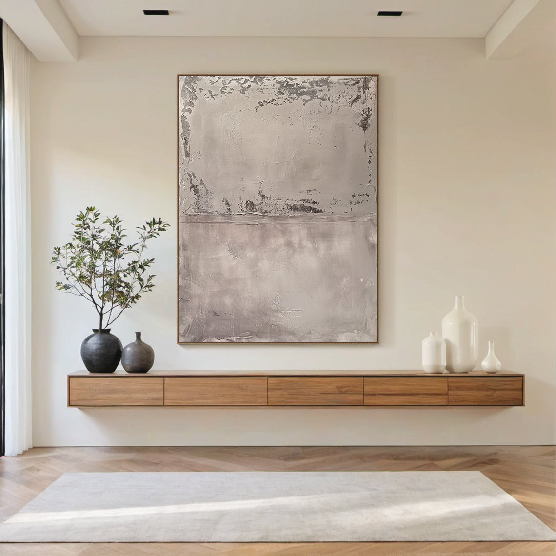 Wabi Sabi Abstract Tactile Impasto Gray Wall Art with Muted Pink Undertones & Distressed Surface (AURA191) - A serene focal point in a bright modern living room. Features layered impasto texture, weathered patterns, soft silvery grays to deep charcoal, subtle pink hints. Displayed against neutral walls, complementing natural light, wooden console, white sofa, and large windows with greenery views. Ideal for minimalist, organic home decor.