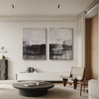 Two-piece Wabi Sabi abstract art set leaning against a white minimalist TV stand in a warm inviting living room. Each canvas features tactile knife strokes, warm neutral tones (soft beige, deep charcoal, earthy brown) with subtle pink undertones, and intentional imperfect textures. The space includes a woven jute rug, a ceramic vase with dried pampas grass, and a soft floor lamp—ideal for creating a cozy, calm living area with natural-inspired charm.