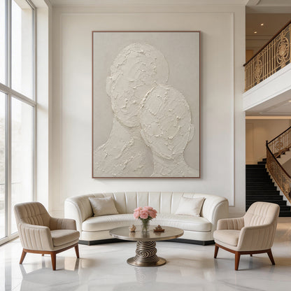 Wabi-sabi beige 3D textured plaster canvas wall art, handcrafted with thick impasto knife strokes, displays two faceless abstract head and neck silhouettes in an intimate leaning snuggling pose. It has raised, cracked, rough tactile texture against a smooth muted warm beige background, with a monochromatic neutral off-white soft taupe palette, a minimalist Japandi figurative artwork fitting calm curated home interior decor.