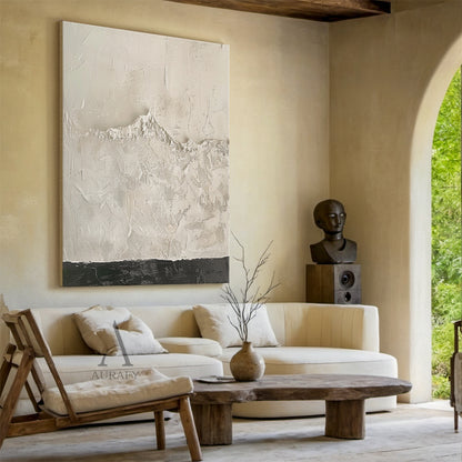 Beige wabi-sabi abstract textured canvas wall art home scene display, handcrafted with heavy impasto knife painting technique. This minimalist Japandi style abstract artwork is dominated by soft warm off-white and light beige tones, with smooth scraped impasto texture on the upper section, rough granular mountain-like raised texture in the middle that faintly reveals the canvas grid, and a narrow deep charcoal textured band at the bottom to balance the visual weight, showing the ideal matching effect when h