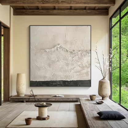 Beige wabi-sabi abstract textured canvas wall art, handcrafted with heavy impasto knife painting technique. The artwork is dominated by soft warm off-white and light beige tones, with smooth scraped impasto texture on the upper section, rough granular mountain-like raised texture in the middle that faintly reveals canvas grid, and a narrow deep charcoal textured band at the bottom to balance the visual weight. It is a minimalist Japandi style abstract piece suitable for neutral home interior decoration.