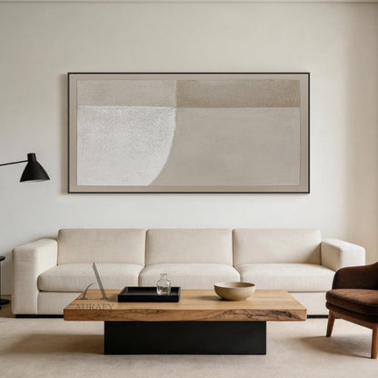 Square Wabi-Sabi beige general abstract canvas wall art AURA737 real bedroom scene display, full-coverage rough sandy impasto textured surface with subtle canvas grain, split into 4 soft-transition neutral beige tonal blocks (bright warm off-white, pale sand, light taupe, muted warm beige), bottom left block with soft curved edge, finished with matching narrow beige border, hung above soft cream linen upholstered queen bed next to small light rattan nightstand with matte ceramic table lamp, against matte su
