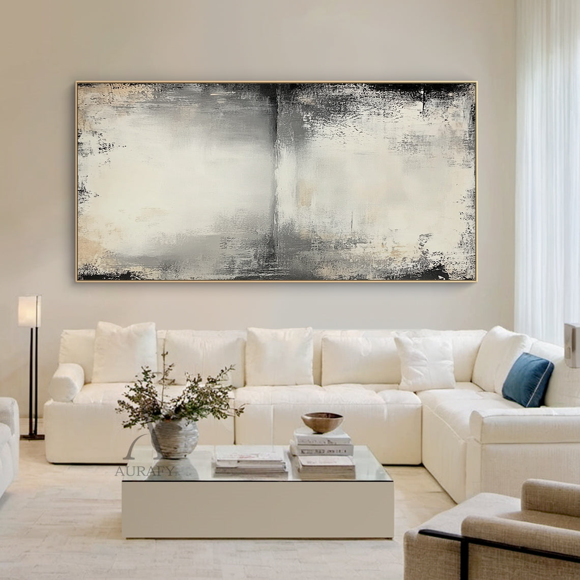 Wabi-sabi beige abstract textured canvas wall art AURA719, styled and displayed hung above a low-profile light oak sideboard in a sun-drenched minimalist Japandi living room scene, features a muted neutral color palette of off-white, pale beige, light to deep charcoal gray with faint warm brown accents, hand-finished distressed brushed & wiped texture with rough worn edges, subtle horizontal abstract sky-water horizon line across the upper middle, natural dark vignette fading from edges to the light beige b
