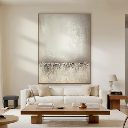 Beige wabi-sabi abstract canvas wall art AURA724 styled in a neutral Japandi home scene. It retains the classic split composition design: the lower section adopts thick rugged impasto texture like weathered rock and dry land with natural uneven edges, the upper left part has a smooth brushed warm beige gradient with faint brush stroke textures, the upper right part comes with subtle etched cross-hatch lines and mottled worn details. The whole work uses monochromatic neutral tones of beige, taupe and off-whi