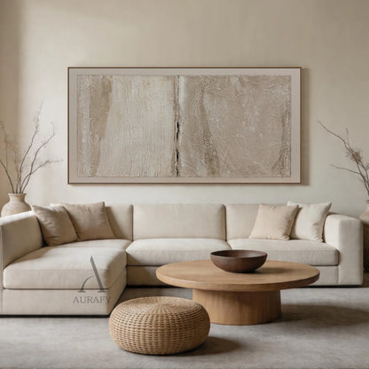 Wabi-Sabi Beige Japandi Minimalist Abstract Canvas Wall Art AURA740, scene display of the artwork mounted on a muted milk coffee living room feature wall, low-saturation warm neutral beige palette with layered light off-white, gray beige and warm taupe tones, textured surface with crinkled paper, natural rock crevice and fabric-like uneven raised details, left area with subtle reflective sheen, right area with matte sandy finish, central raised dark vertical split as visual focal point, outlined with thin b