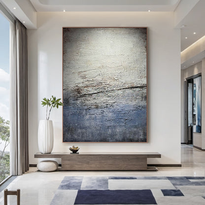 Wabi Sabi Gray Blue Abstract Textured Wall Art AURA225 - Vertical canvas with cracked layered finish in muted grays, soft blues & warm neutrals, styled as a focal point in a sunlit home office. Ideal home office statement piece, dining room wall accent or hallway decor. Complements minimalist, contemporary or Scandi decor styles. Adds depth & serenity to modern interiors, merging organic imperfection with modern elegance for timeless charm.