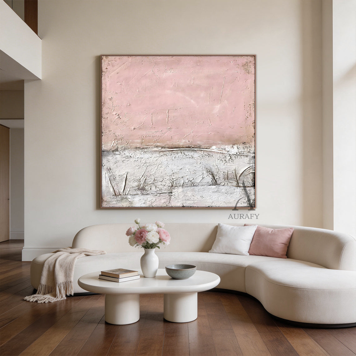 WABI SABI Pink Abstract Textured Wall Art (AURA245) - Soft Blush Upper Half with Visible Brush Strokes & Imperfections, Lower Half in White & Neutral Cracked Layered Finish. Framed in Thin Light Wood Frame. Displayed in Modern Cozy Living Room: Gray Sofa with Pink Cushion, White Vase with Black Accents, Natural Light from Large Window. Perfect for Minimalist Home Decor, Wabi Sabi Inspired Living Space Accent, Cozy Living Room Wall Decor. AURA245 Collection Merges Wabi Sabi Charm with Modern Minimalism to El